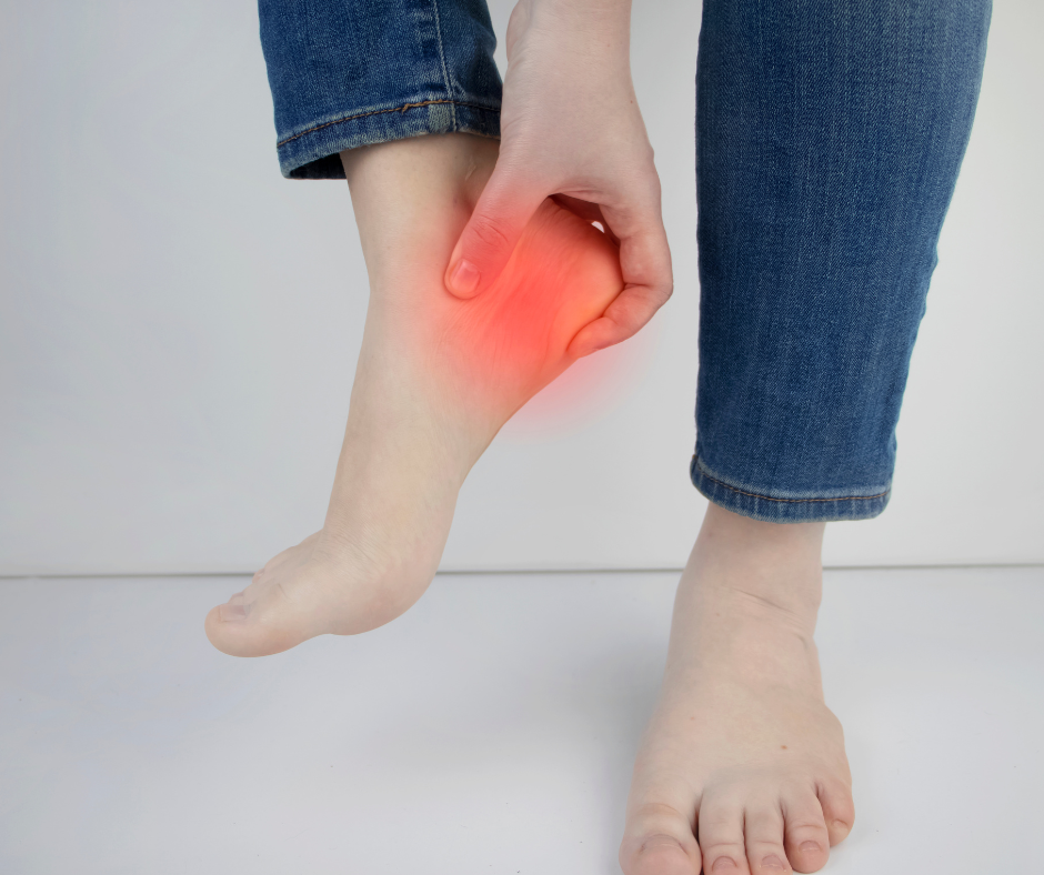 person lifting up foot that has heel pain that is highlighted in red